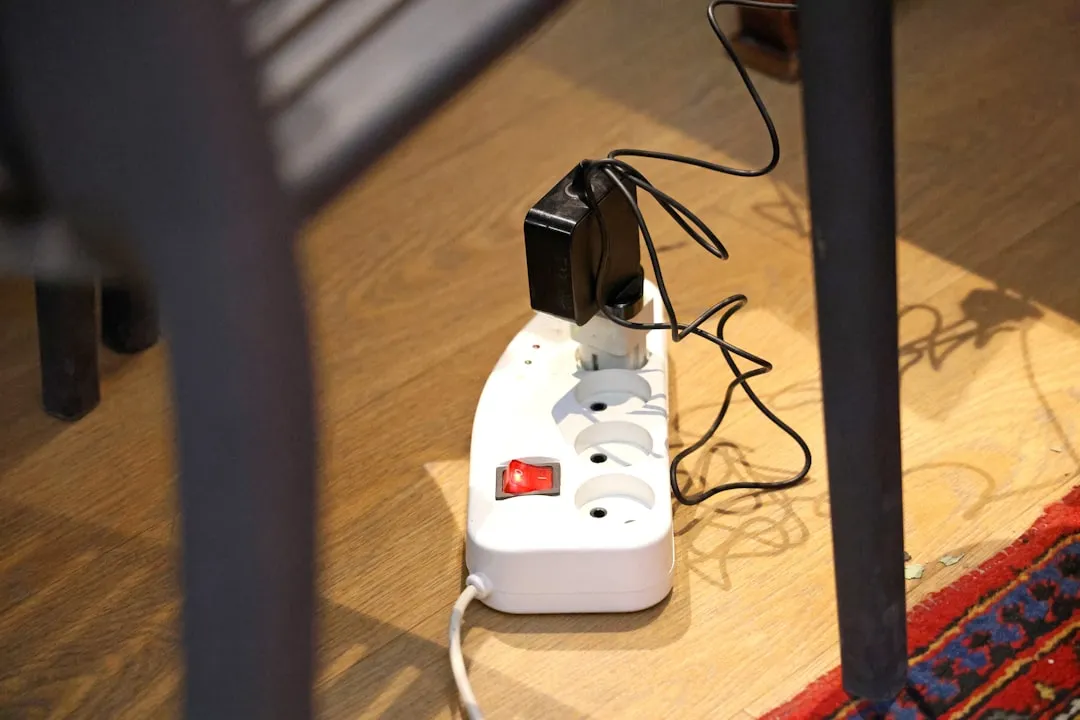 床に置かれた白い電源タップと、そこに挿さった複数のプラグ