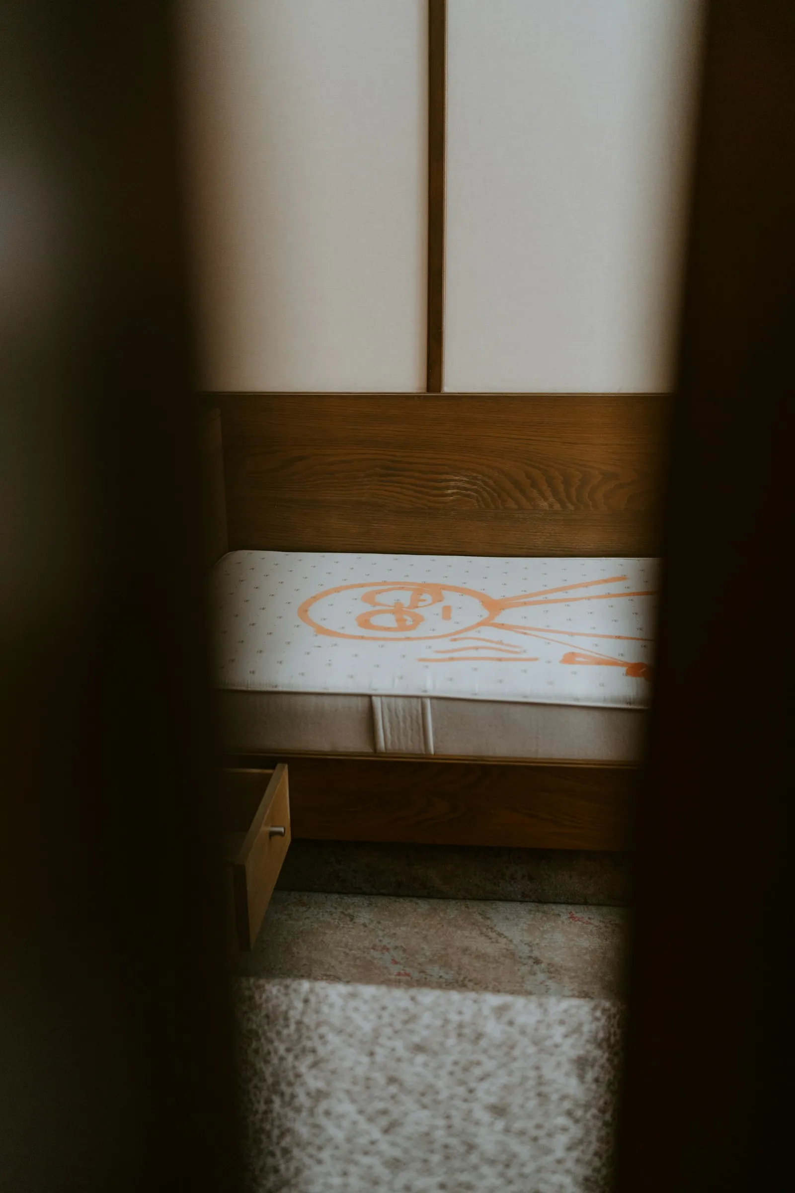 障子のある部屋に置かれたベッドと、その下から引き出された木製の引き出し